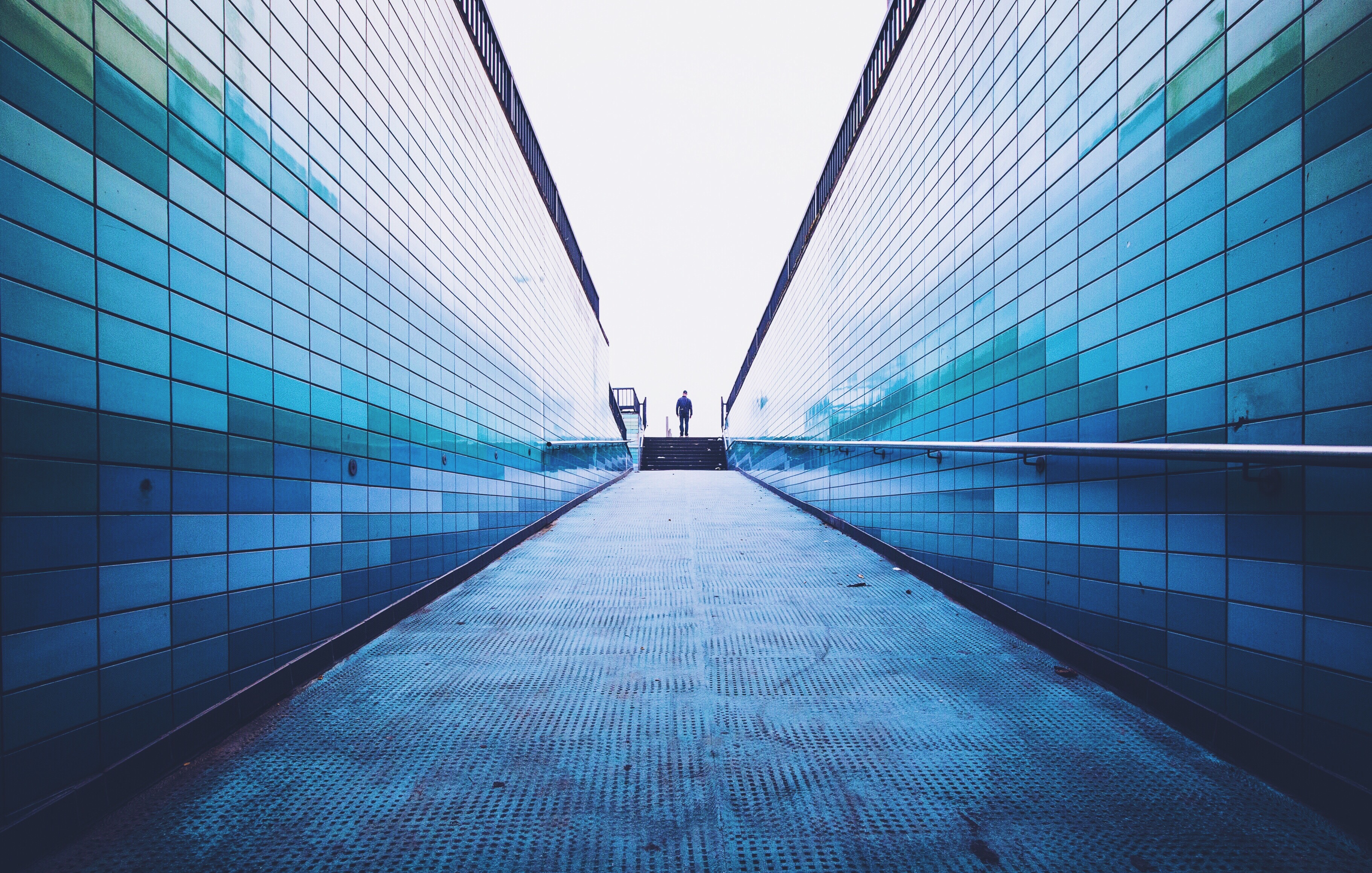 Man Walking On Footpath Amidst Surrounding Wall